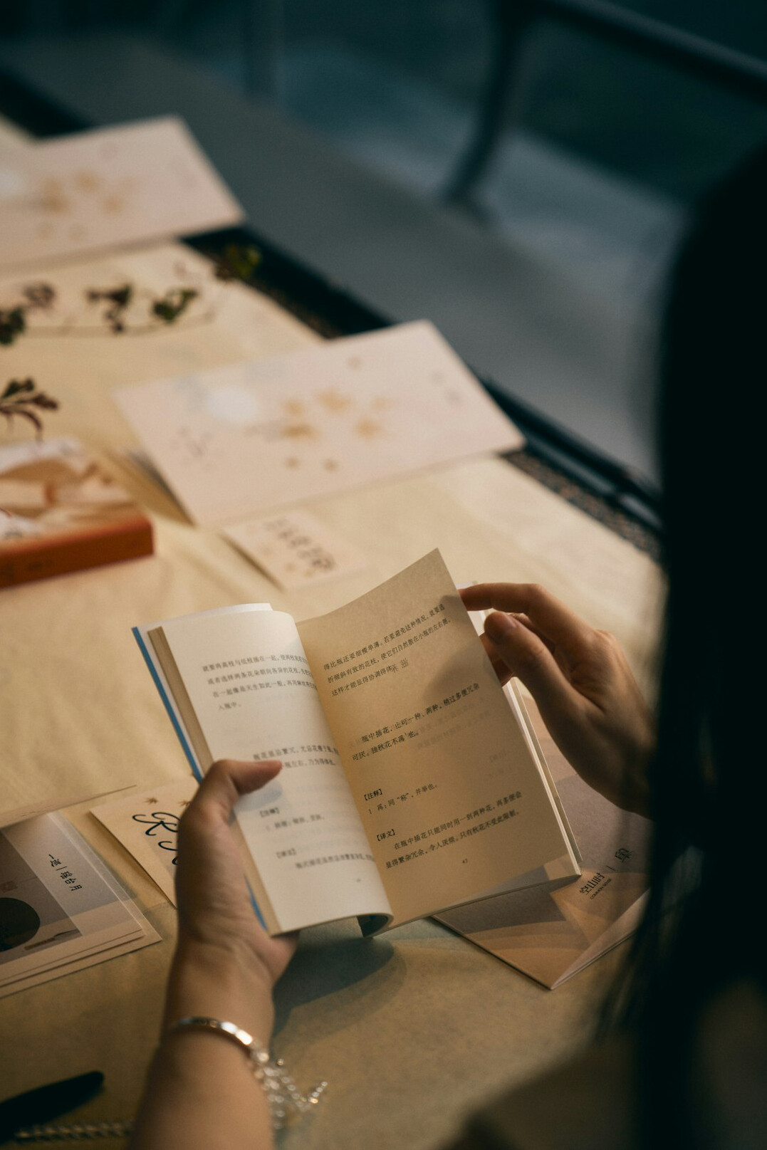 Researcher writing notes surrounded by open books